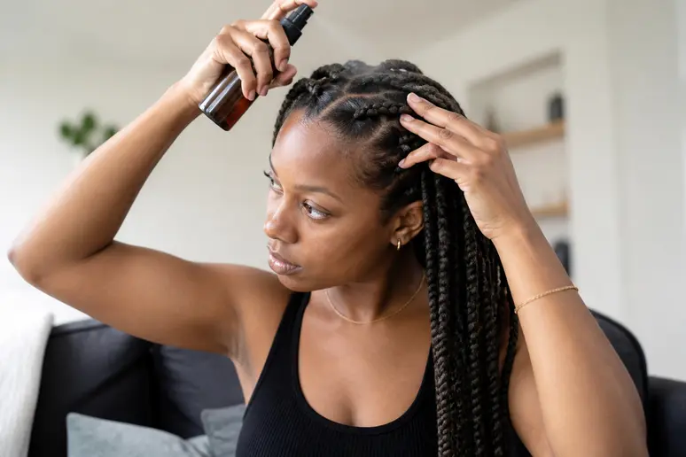 Application d'un soin hydratant en spray sur des tresses pour l'entretien des cheveux texturés