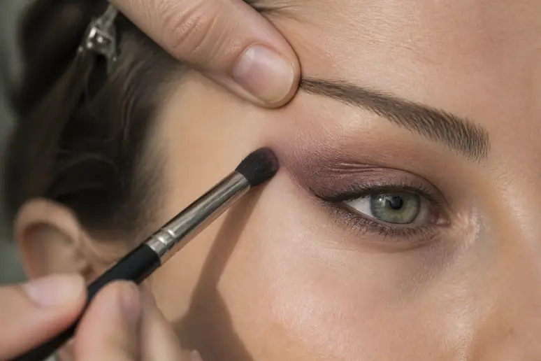Application d'un fard prune en coin externe pour sublimer les yeux verts
