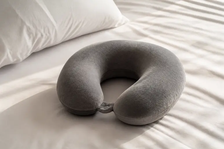 Coussin de voyage ergonomique posé sur un lit pour protéger l'oreille des pressions nocturnes
