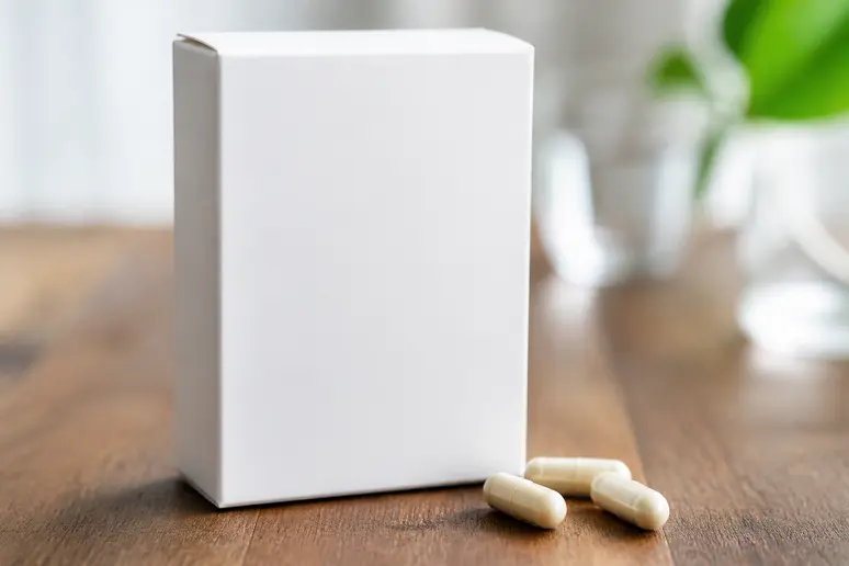 Boîte de compléments alimentaires pour cheveux avec gélules posées sur une table en bois