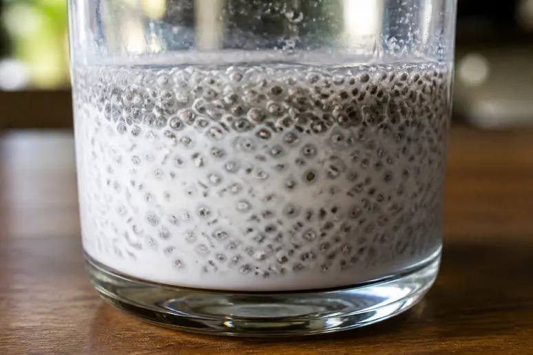 Graines de chia en train de tremper dans un verre de lait végétal pour activer leur mucilage.