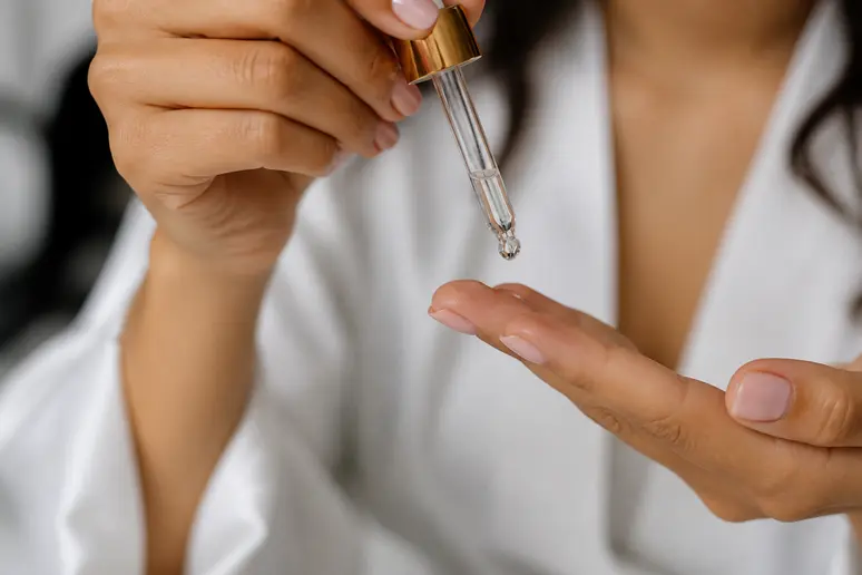 Application d'une goutte minime de sérum tenseur sur le bout des doigts avant application